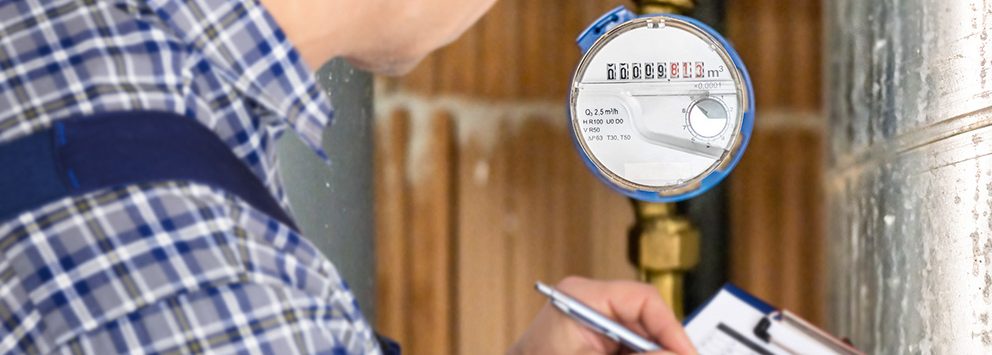 Mann ließt Wasseruhr ab und trägt die Zahlen ein